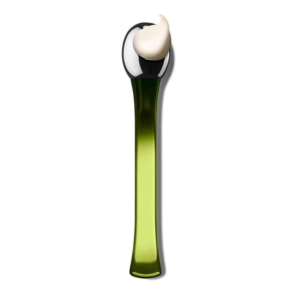 Grüner Applikator mit metallischem Kopf, auf dem sich eine cremefarbene Substanz befindet.