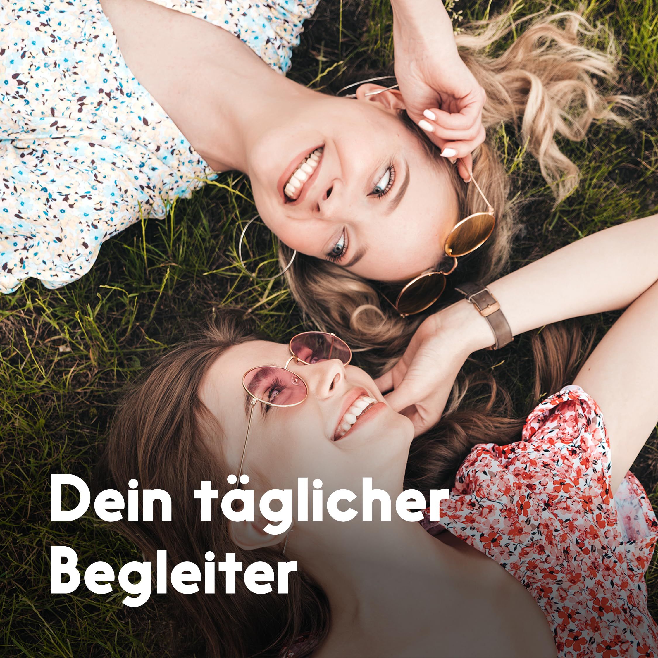 Zwei lachende Frauen liegen im Gras, eine hält Sonnenbrillen. Text: Dein täglicher Begleiter.