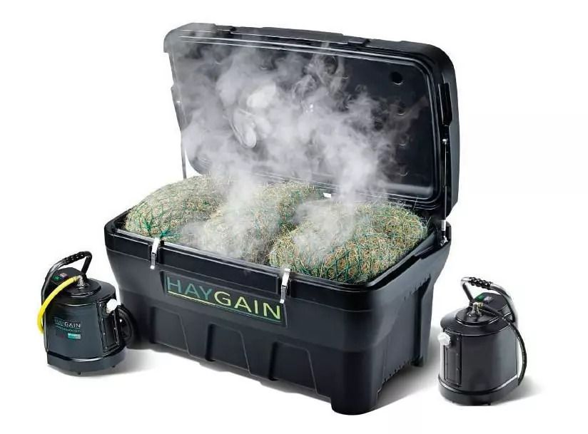 Schwarzer Behälter mit Heu und Dampf. HAYGAIN-Logo. Zwei Dampfer seitlich.