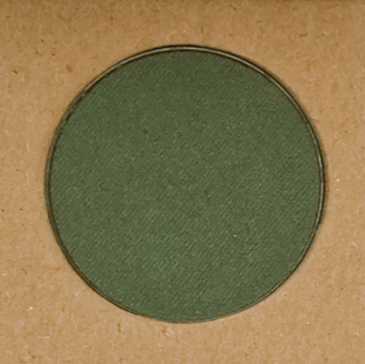 Grüner Lidschatten in runder Form, in einer Pappschachtel.