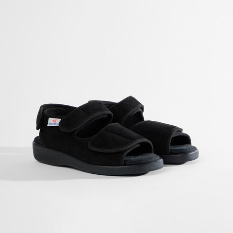 Schwarze Sandale mit Klettverschluss, offenem Zehenbereich und einem kleinen roten Logo auf der Seite.