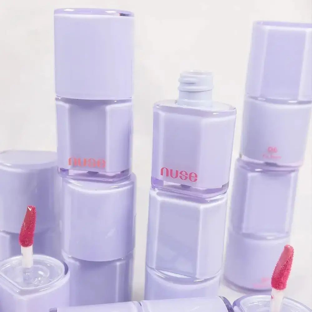 Mehrere Lipgloss-Flakons in lila Verpackung. Aufschrift "nuse".