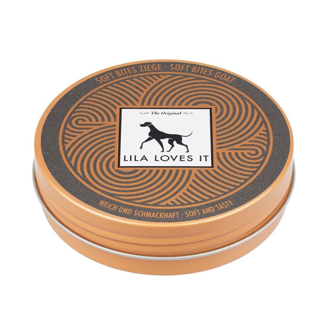 Runde Dose mit Aufschrift "LILA LOVES IT". Deckel mit braunen Verzierungen und Produktnamen. Text: "WEICH UND SCHMACKHAFT".