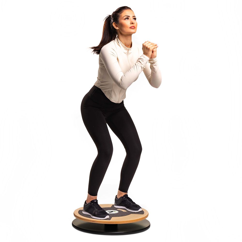 Frau in Sportkleidung steht auf zwei Balance-Discs und führt eine Kniebeuge aus.
