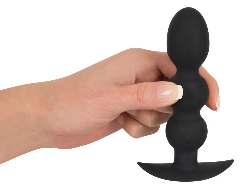 Hand hält schwarzes, perlenförmiges Silikonprodukt mit Basis. Auf weißem Hintergrund.