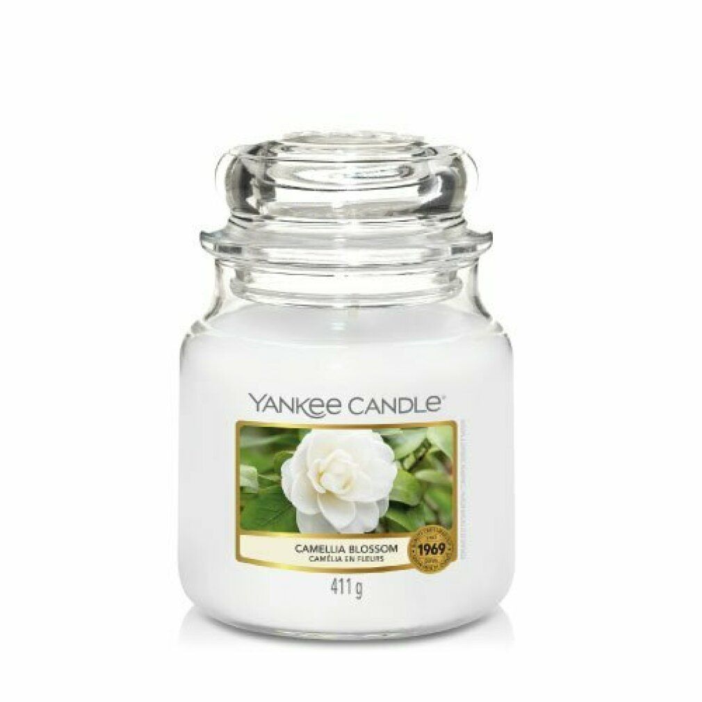 Weißes Kerzenglas mit Deckel. Etikett mit Blüte und Schriftzug. Aufschrift: Yankee Candle, Camellia Blossom, 411g.