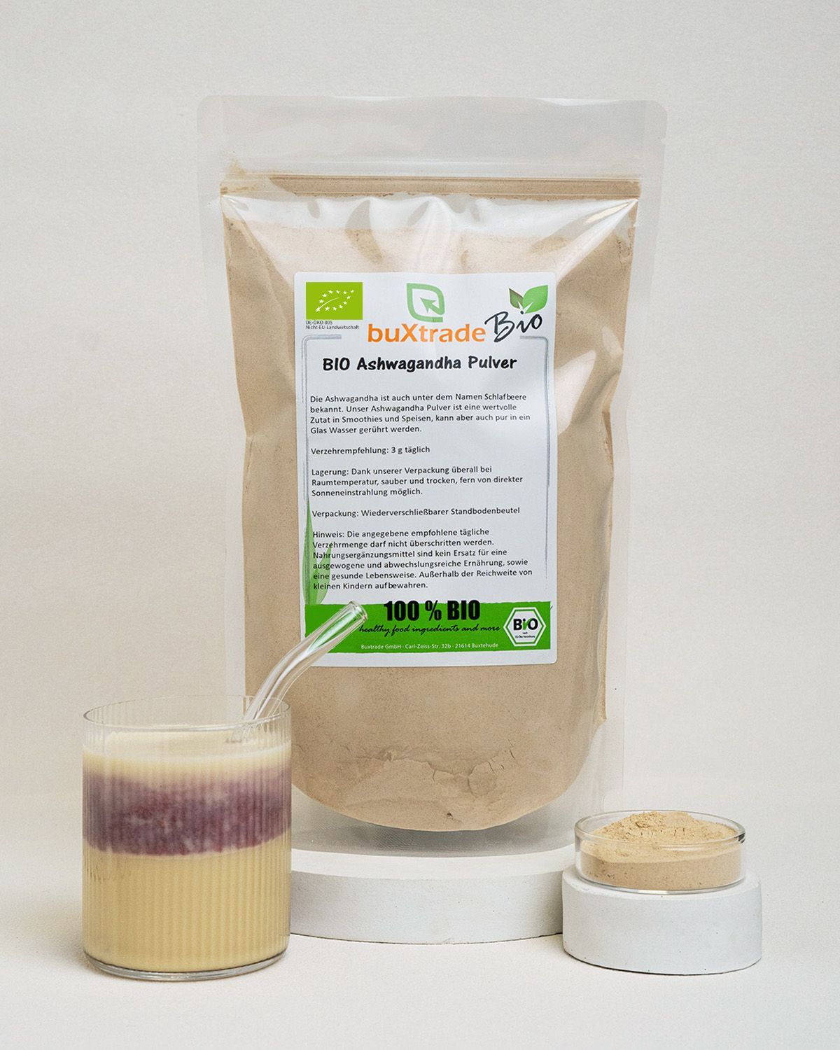 Buxtrade Bio Ashwagandha Pulver in einem Standbodenbeutel mit einem Glas Ashwagandha-Milch und einer kleinen Schale Pulver.