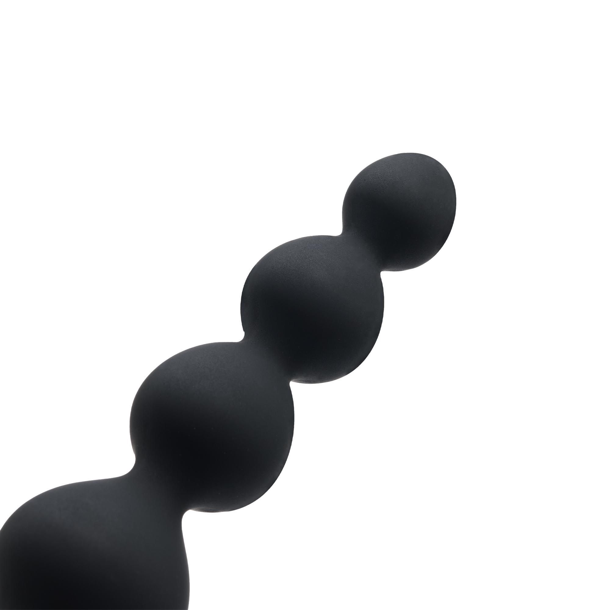 Nahaufnahme der schwarzen, vibr. Anal-Kette. Mehrere Kugeln unterschiedlicher Größe.