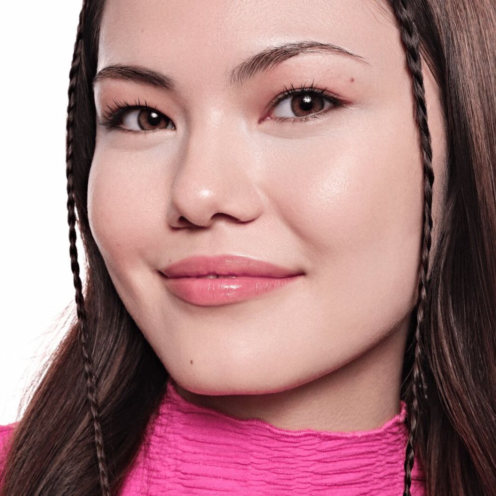 Porträt einer Frau mit Make-up. Hautton, Lippenstift, Augenbrauen. Zöpfe im Haar. Rosa Oberteil.