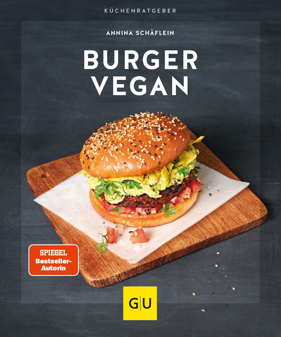 Ein veganer Burger auf einem Holzbrett. Oben steht "Burger Vegan". Auf dem Brett liegt ein weißes Papier. Rechts unten das Logo "GU".