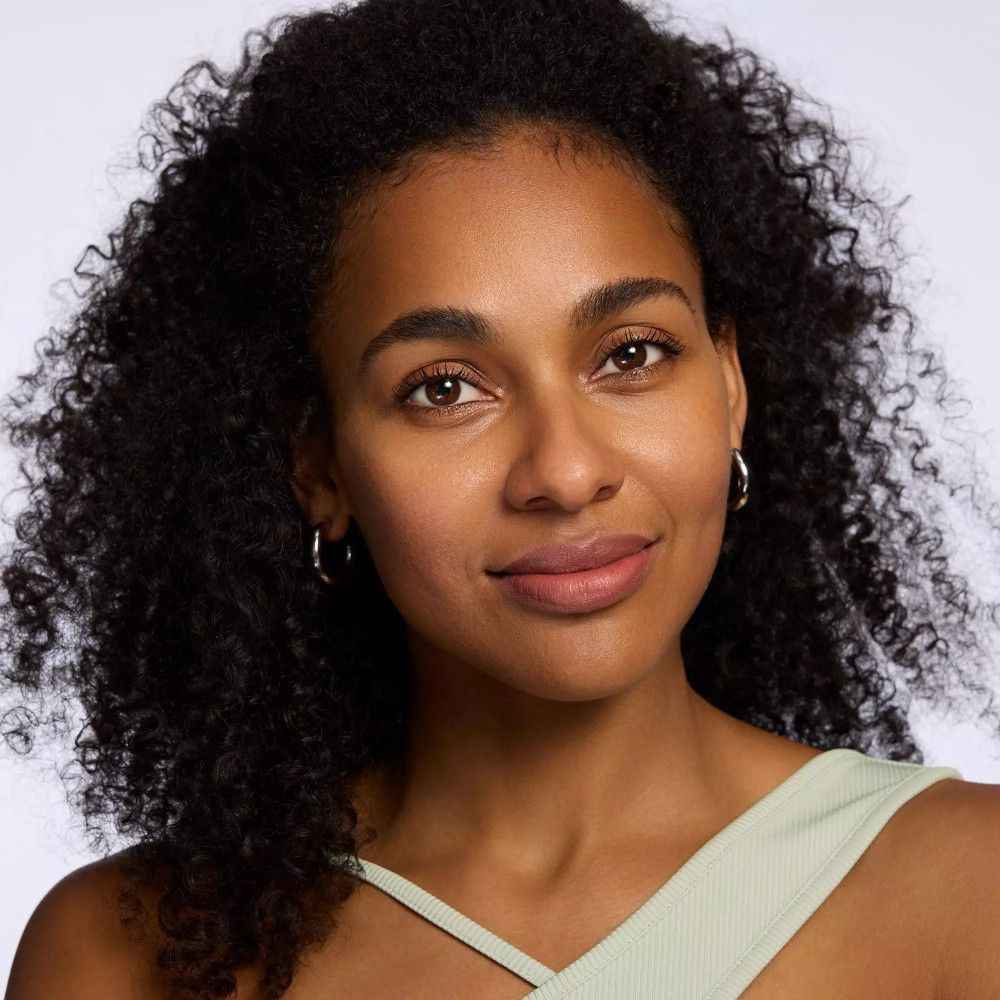 Porträt einer Frau mit lockigem, dunklem Haar. Sie trägt einen grünen Top.