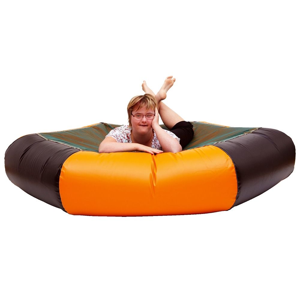 Person liegt auf einem sechseckigen Trampolin. Grüne Sprungfläche, schwarzer Rand und orangefarbene Seitenwand.