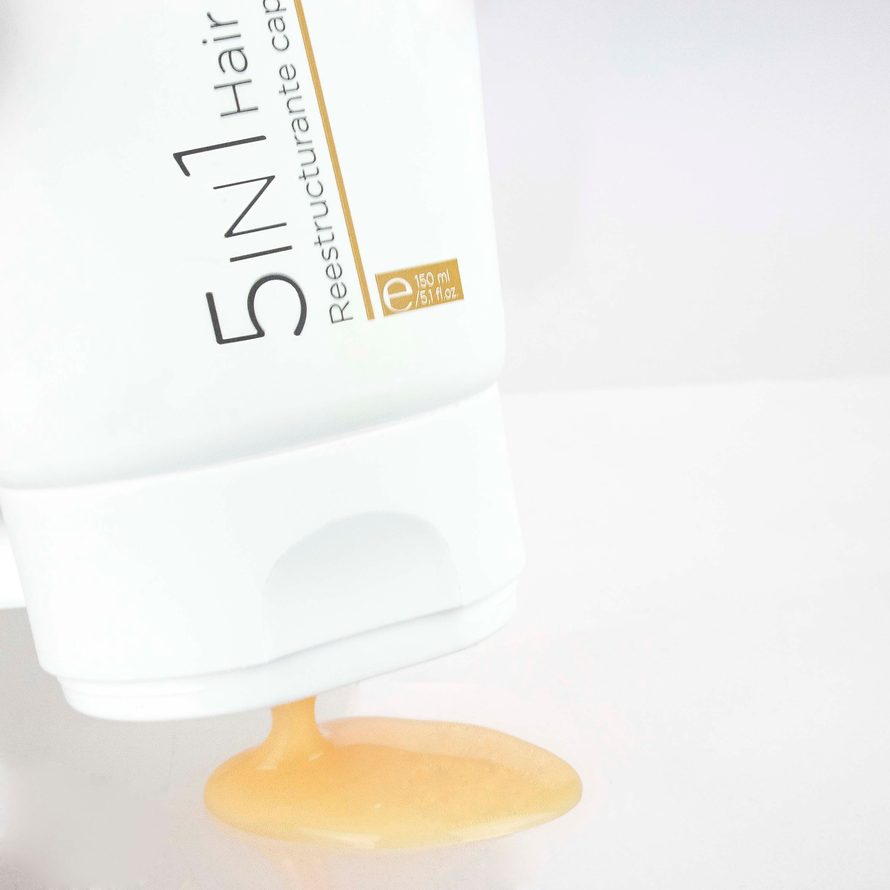 Weiße Tube, Produkt wird ausgegossen. Text: 5 in 1 Hair Restorer. Marke: Postquam. Gelbe Flüssigkeit.