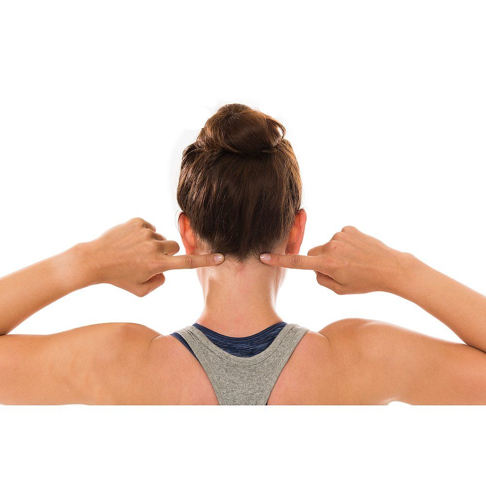 Frau zeigt mit Zeigefingern auf ihren Nacken. Grauer Hintergrund.