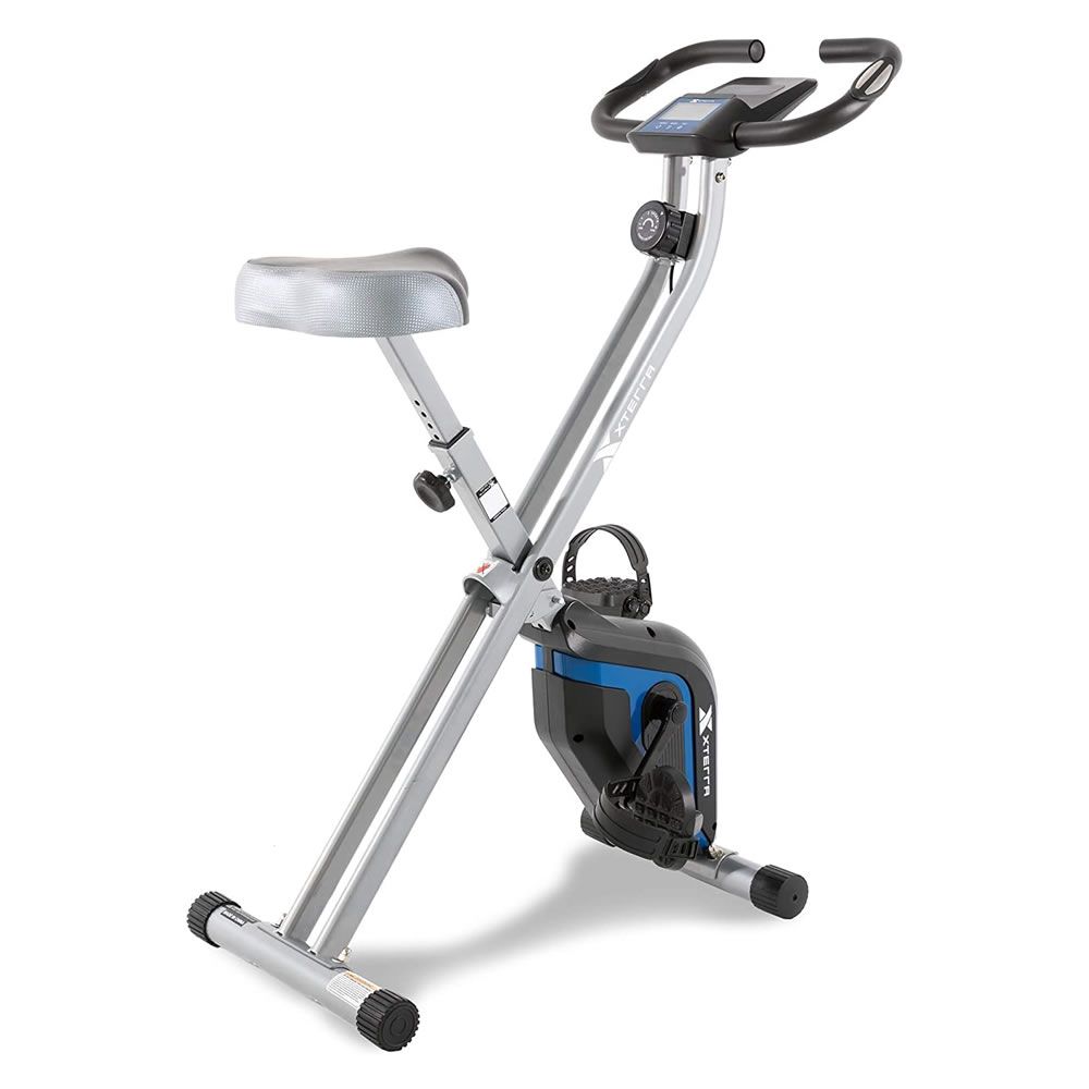 Klappbarer Heimtrainer. Silberner Rahmen, schwarze Griffe, blauer Akzent. Sitz und Pedale sichtbar.