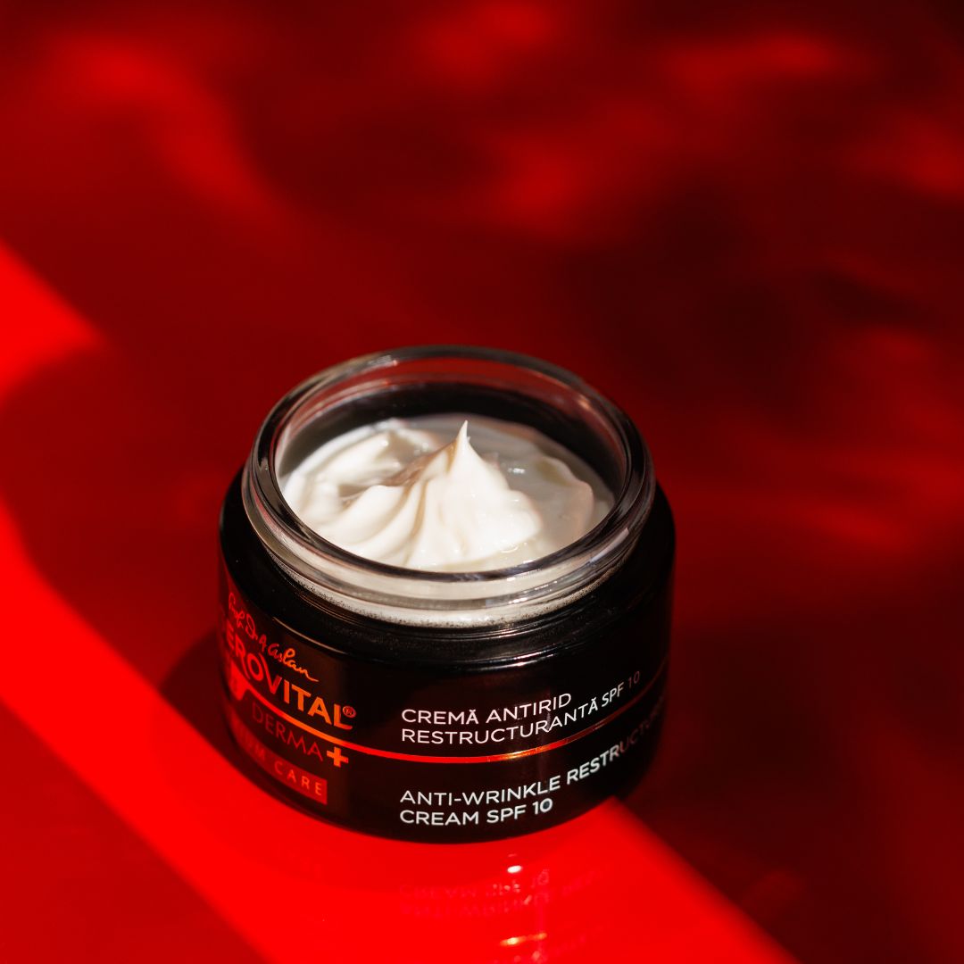 Offener schwarzer Cremetiegel mit weißer Creme auf rotem Hintergrund. Text: Gerovital H3 Derma+, Anti-Falten Restrukturierungscreme SPF10.
