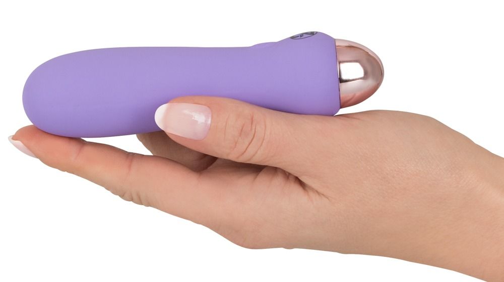 Lila Vibrator in einer Hand gehalten. Rosafarbener Kopf. Glatte Oberfläche.