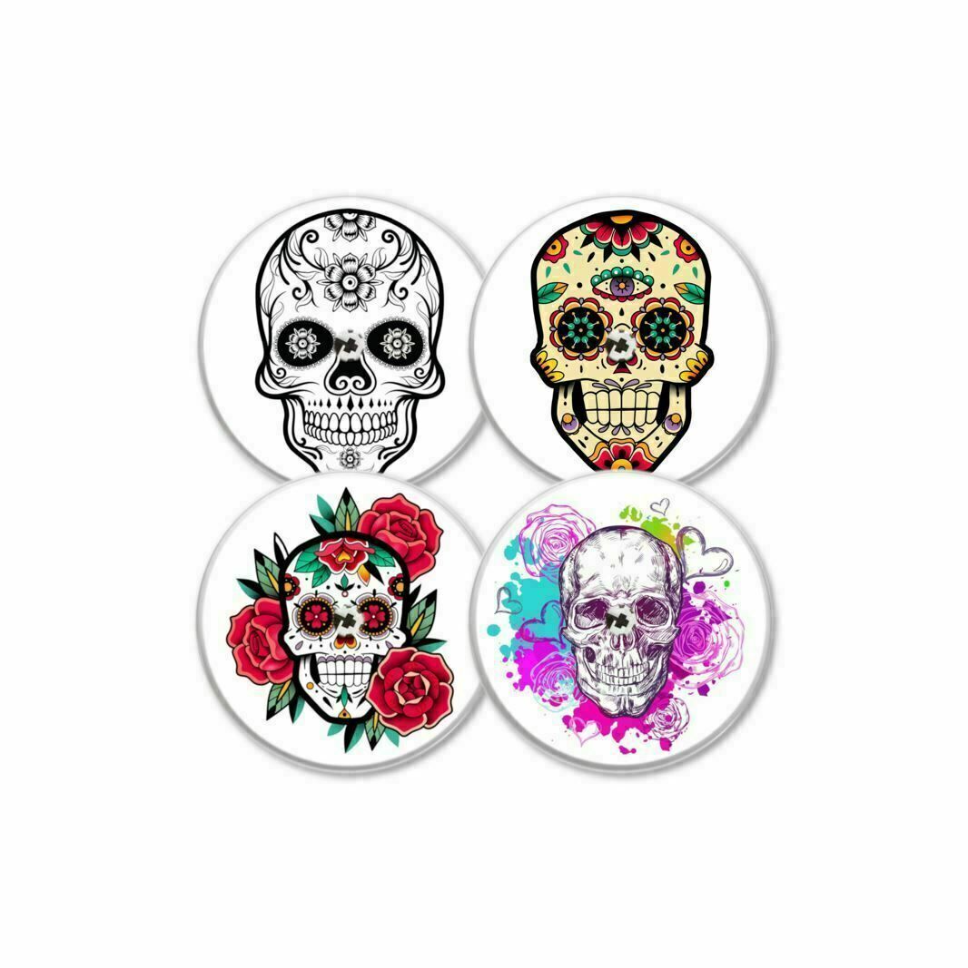 Vier runde Aufkleber mit Totenkopf-Designs. Verschiedene Farben und Muster, darunter Blumen und Verzierungen.