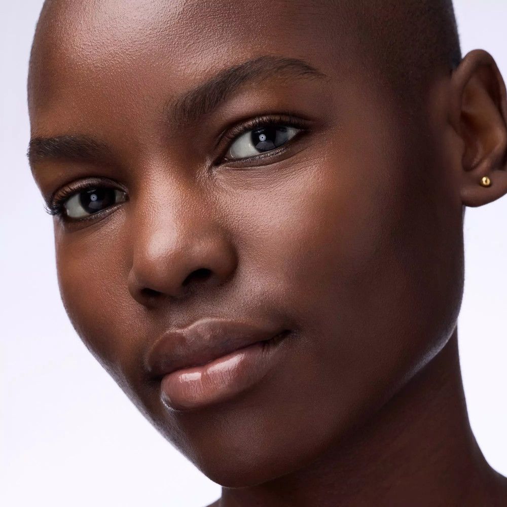 Porträt einer Frau mit dunkler Haut. Aufgetragenes Lippenprodukt, glänzend.