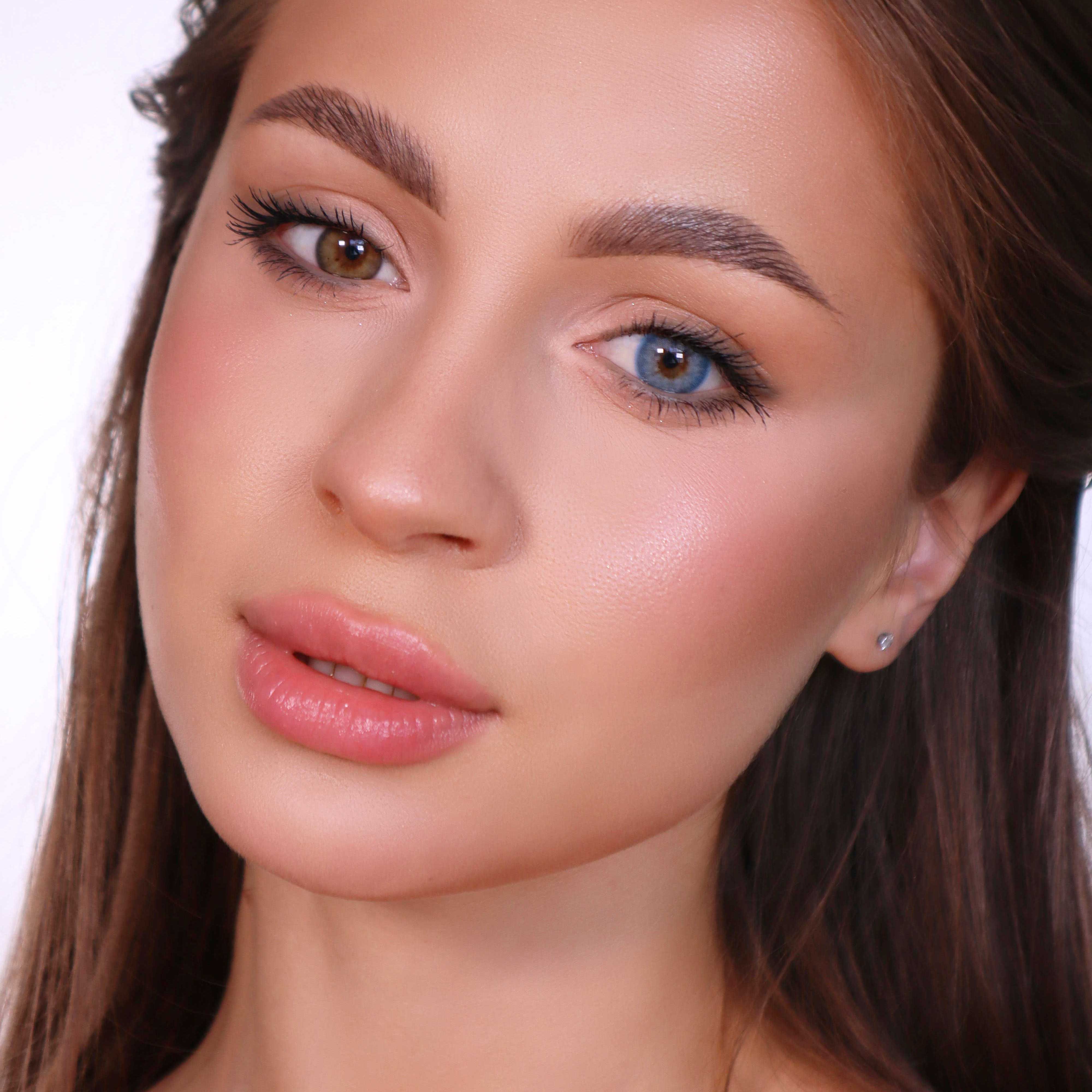 Porträt einer Frau mit zwei verschiedenfarbigen Augen. Ein Auge ist braun, das andere blau. Die Frau hat lange braune Haare.