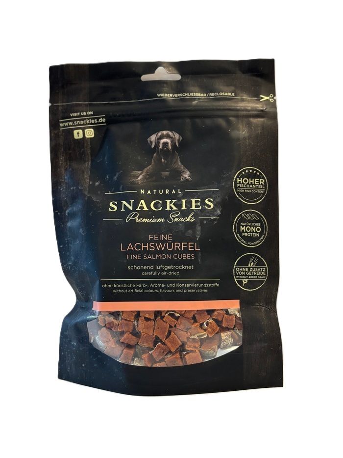 Verpackung mit Lachswürfeln. Schwarze Tüte mit Produktname, Hundefoto und Logos. Sichtfenster zeigt Würfel. Text: Feine Lachs-Würfel.