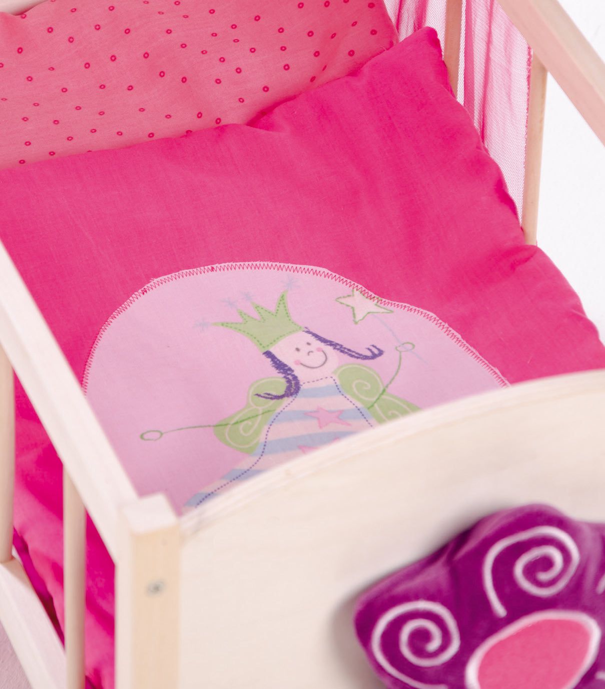 Puppenstandbett mit rosa Bettwäsche und Kissen. Auf dem Kissen ist eine Prinzessin abgebildet. Lila Pfoten-Kissen.