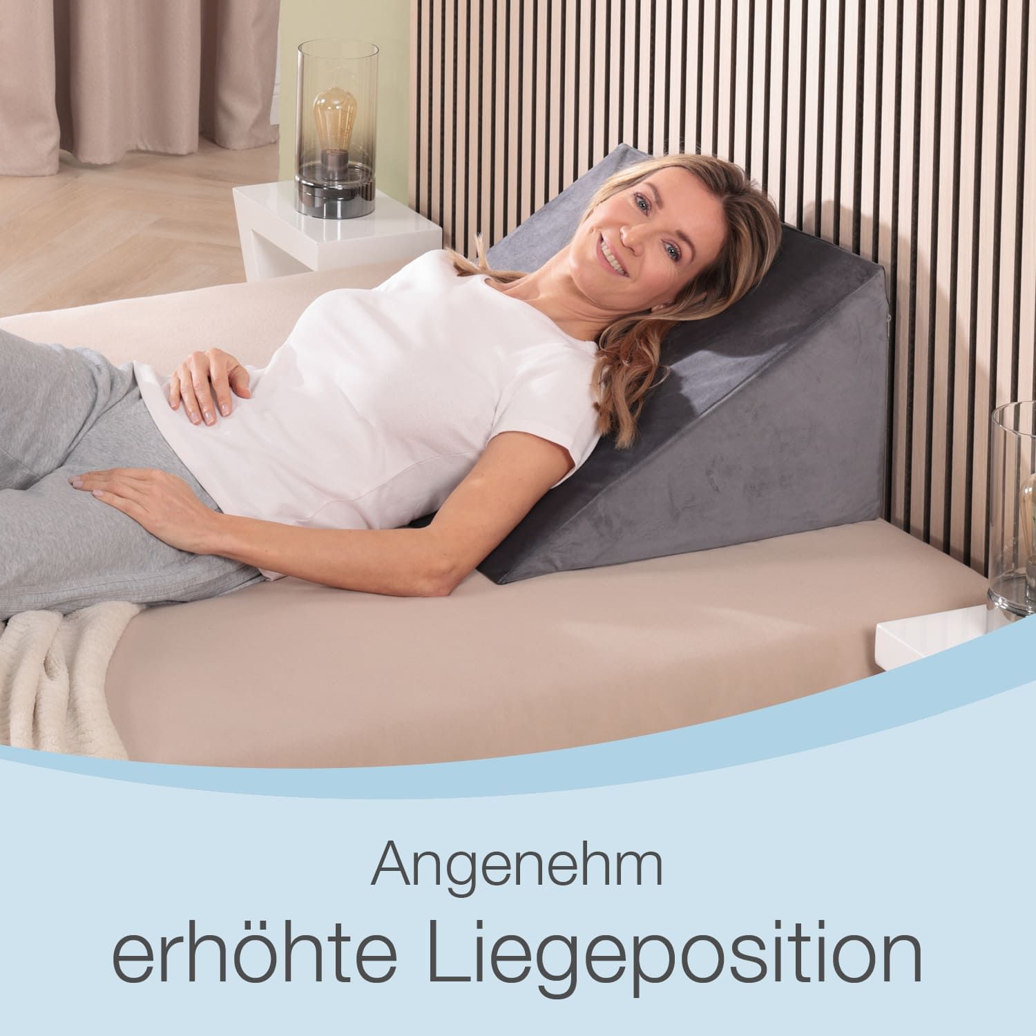 Frau liegt auf Bett mit Keilkissen. Text: Angenehm erhöhte Liegeposition. Holzlattenwand im Hintergrund.