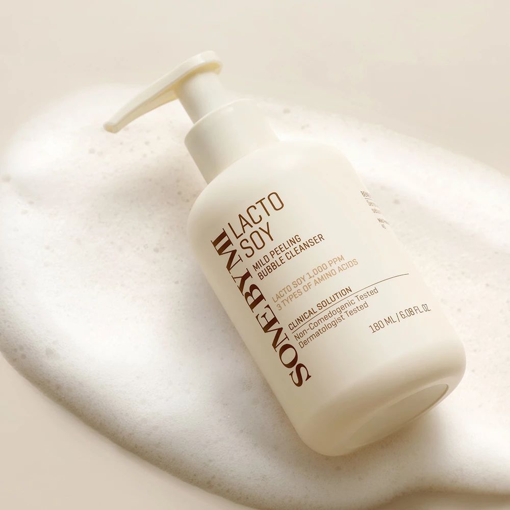 Eine Flasche mit Pumpe liegt in Schaum. Aufschrift: LACTO SOY Mild Peeling Bubble Cleanser. Marke: SOMEBYMI.