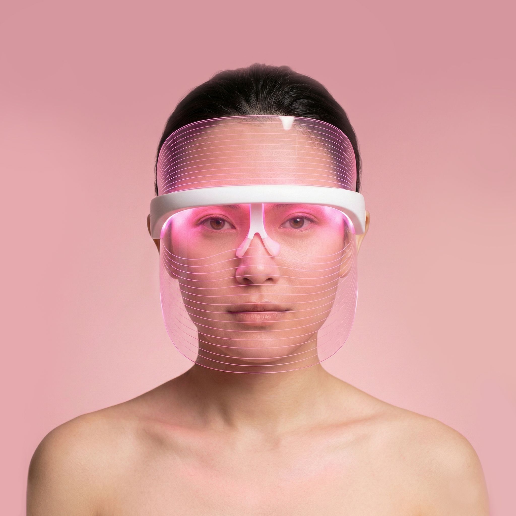 Frau mit einer leuchtenden LED-Gesichtsmaske in Rosa.