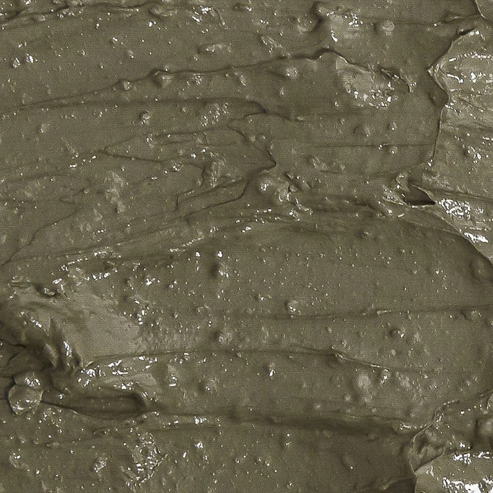 Textur einer graugrünen Tonmaske mit sichtbaren Schlieren und Wellen.