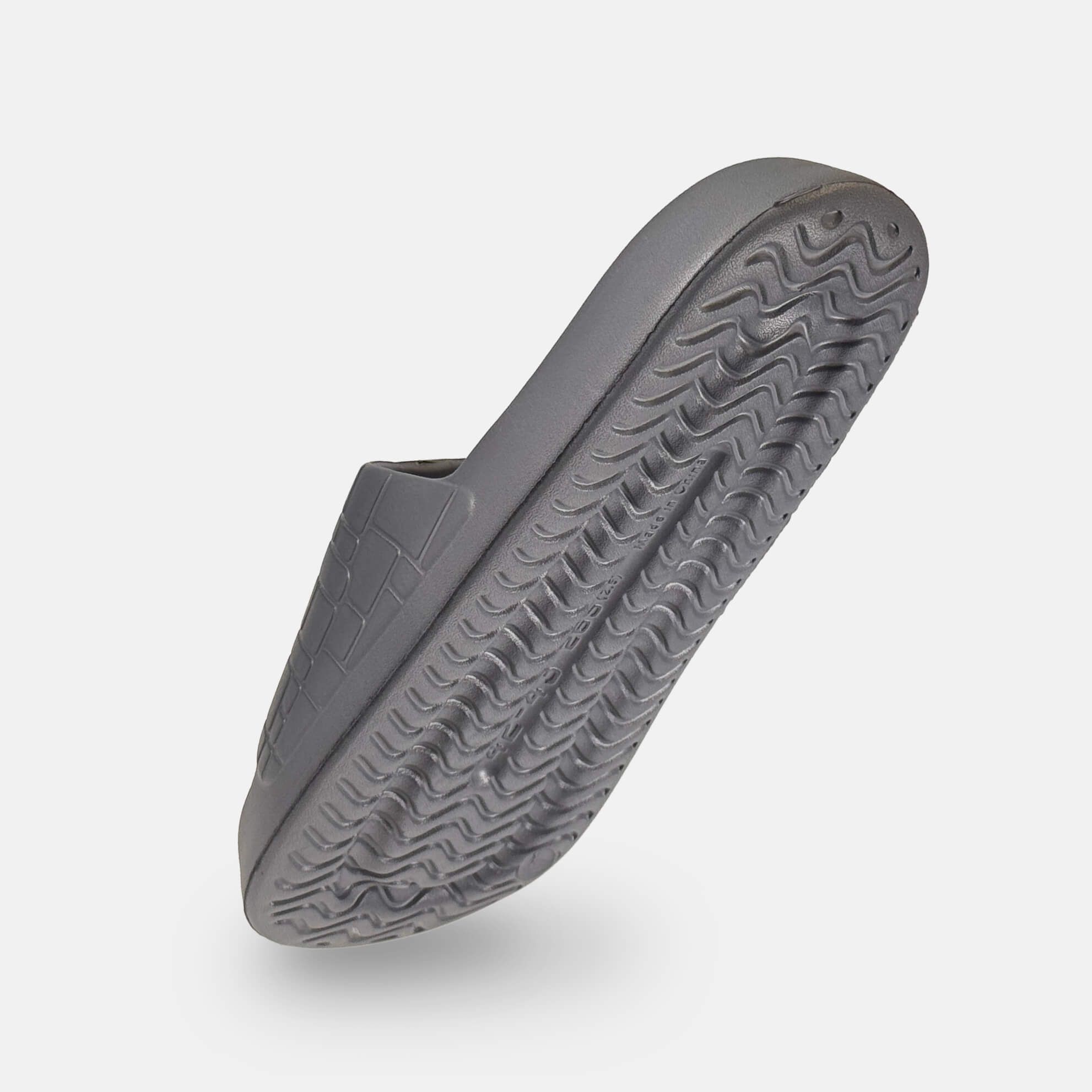 Graue Pantolette von unten gesehen. Wellenförmige Sohle. Quadratisches Muster auf dem Riemen.