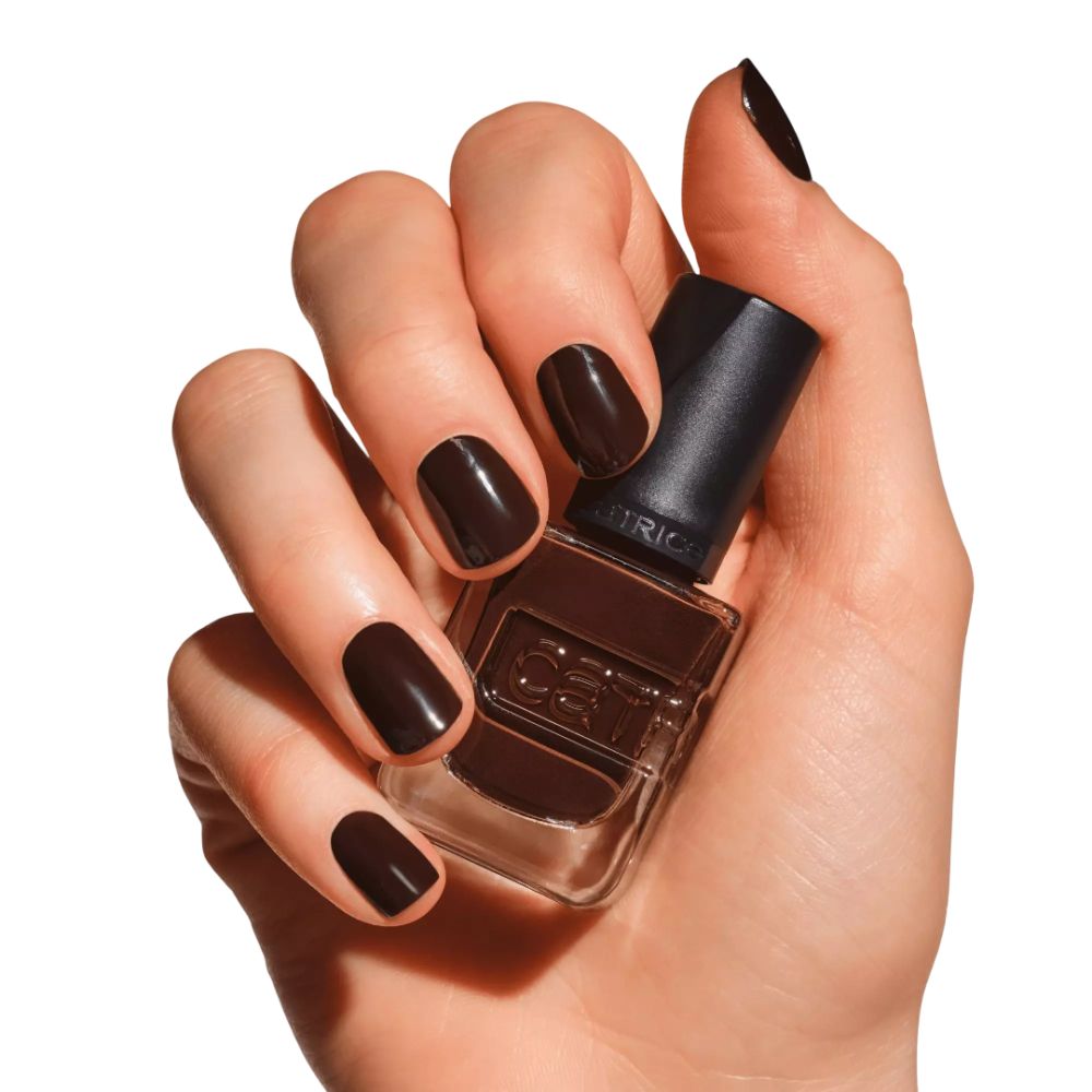 Hand hält Nagellackflasche. Nägel mit braunem Nagellack lackiert. Der Markenname CATRICE ist sichtbar.