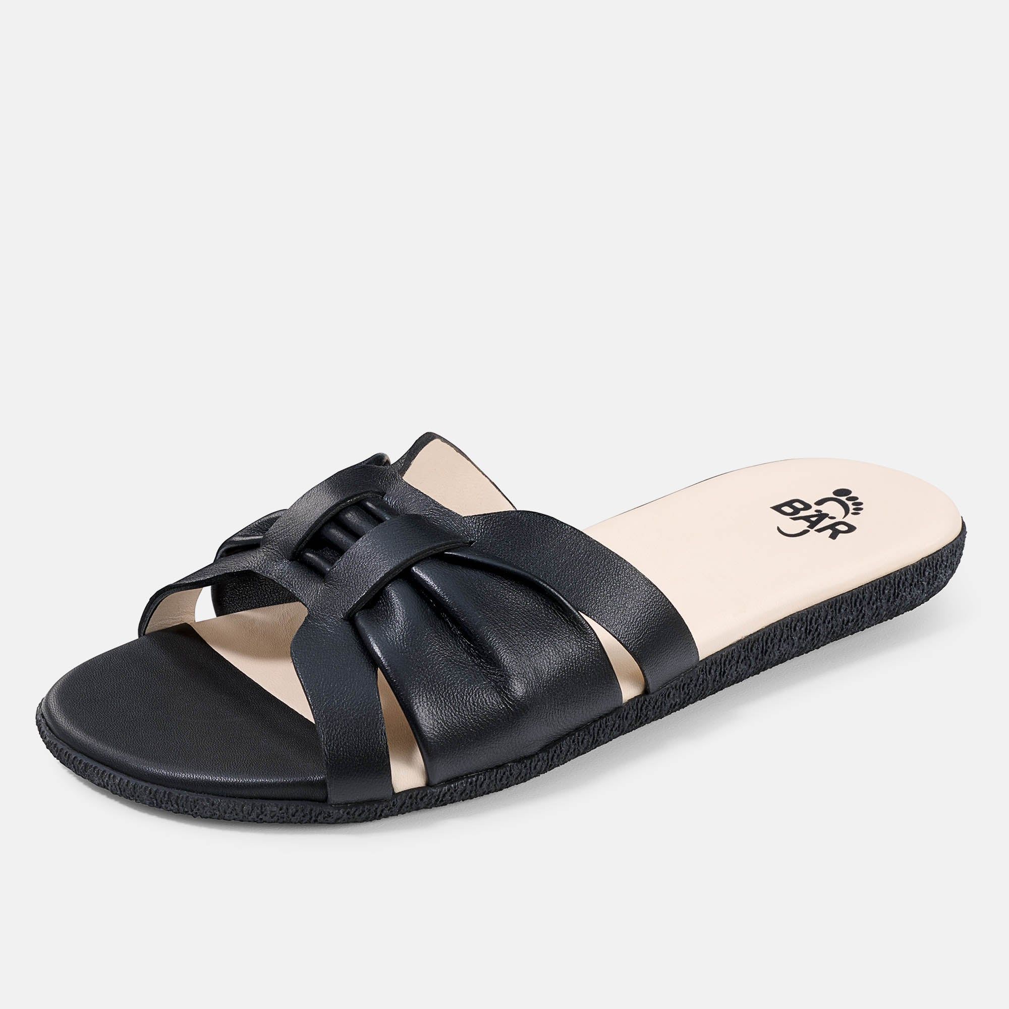 Schwarze Pantolette mit gekreuzten Riemen. Beige Innensohle mit Logo. Breite Form.