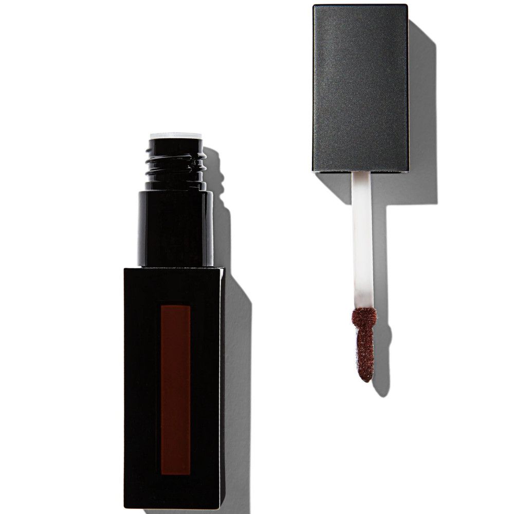 Geöffnete Lipgloss-Verpackung. Schwarzer Behälter mit braunem Inhalt. Applikator mit brauner Spitze daneben.