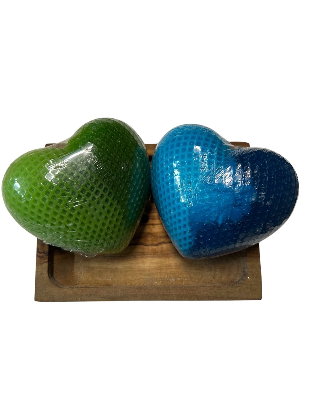 Zwei herzförmige Seifen, eine grün, eine blau, auf einem Holztablett.