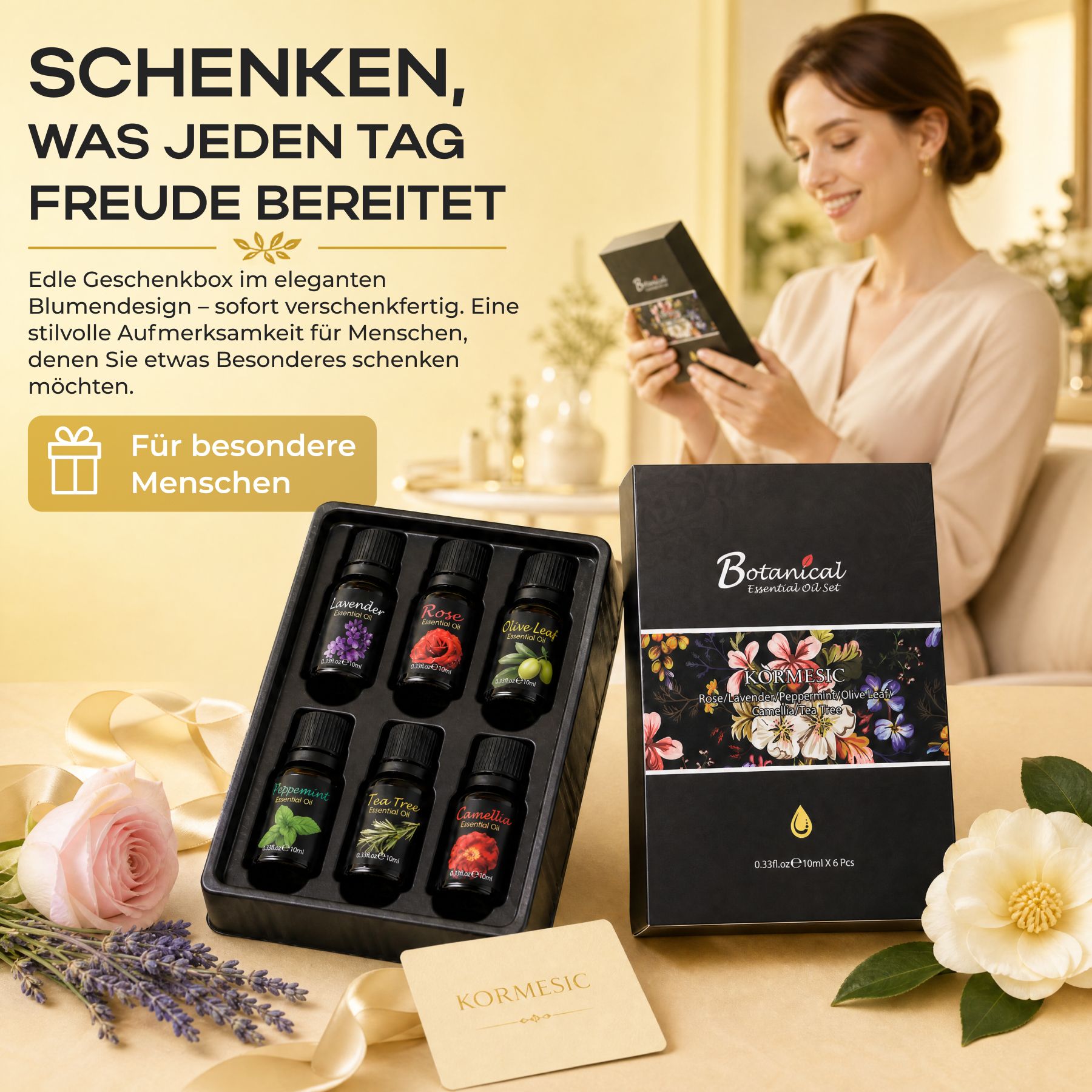 Eine Frau öffnet eine Geschenkbox mit sechs kleinen Flaschen ätherischer Öle, daneben eine geschlossene Geschenkbox und Blumen.