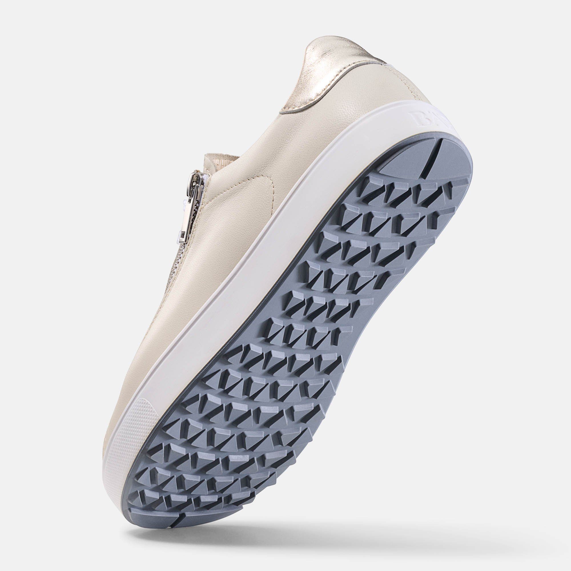 Beige Schuh mit Reißverschluss, weißer Sohle und grauem Profil. Goldfarbener Akzent an der Ferse.