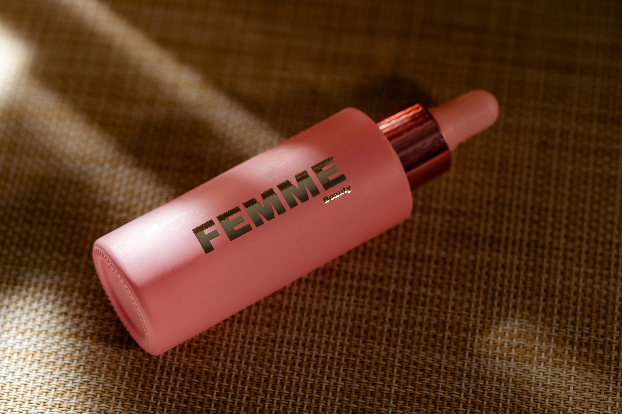 FEMME Advanced Repair Face Serum mit Propolis: Rosa Glasflasche mit Pipette und roségoldfarbenem Verschluss.
