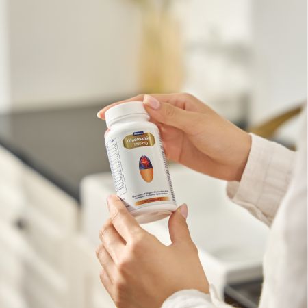 Hände halten eine Flasche Belnutris Glucosamin+ 1750mg. Goldfarbenes Etikett mit Produktinformationen. Aufschrift: Glucosamin, Collagen, Chondroitin, MSM.