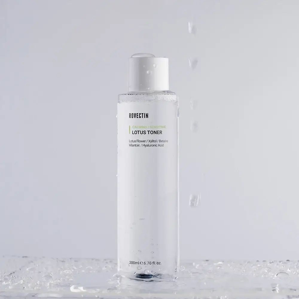 Transparente Flasche mit weißem Deckel. Aufschrift: ROVECTIN Calming Lotus Toner. Wassertropfen fallen. Unten: 200ml 6.76 fl. oz.
