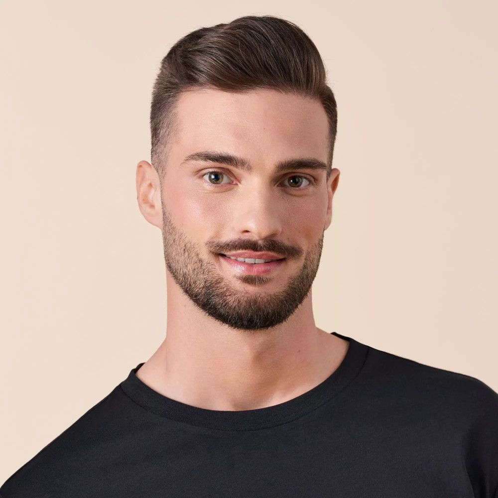 Porträt eines Mannes mit Bart. Er trägt ein schwarzes T-Shirt und blickt in die Kamera.