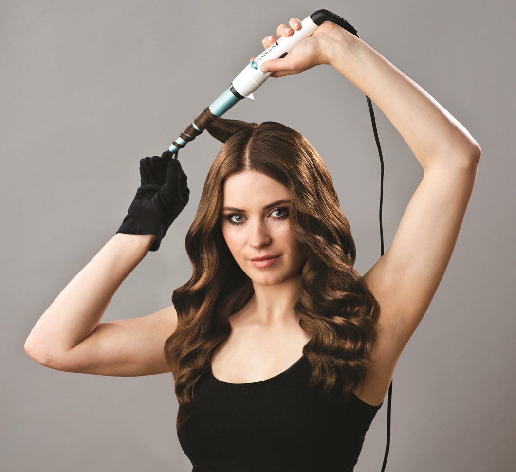 Frau mit Locken, Lockenstab in der Hand. Schwarzer Handschuh. Produkt: Remington Shine Therapy.