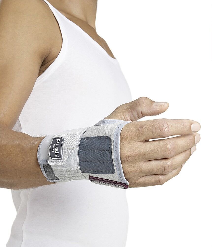 Person trägt Handgelenkbandage. Weiß-grau, mit Klettverschluss. Push-Logo sichtbar. Handgelenk in leichter Beugung.