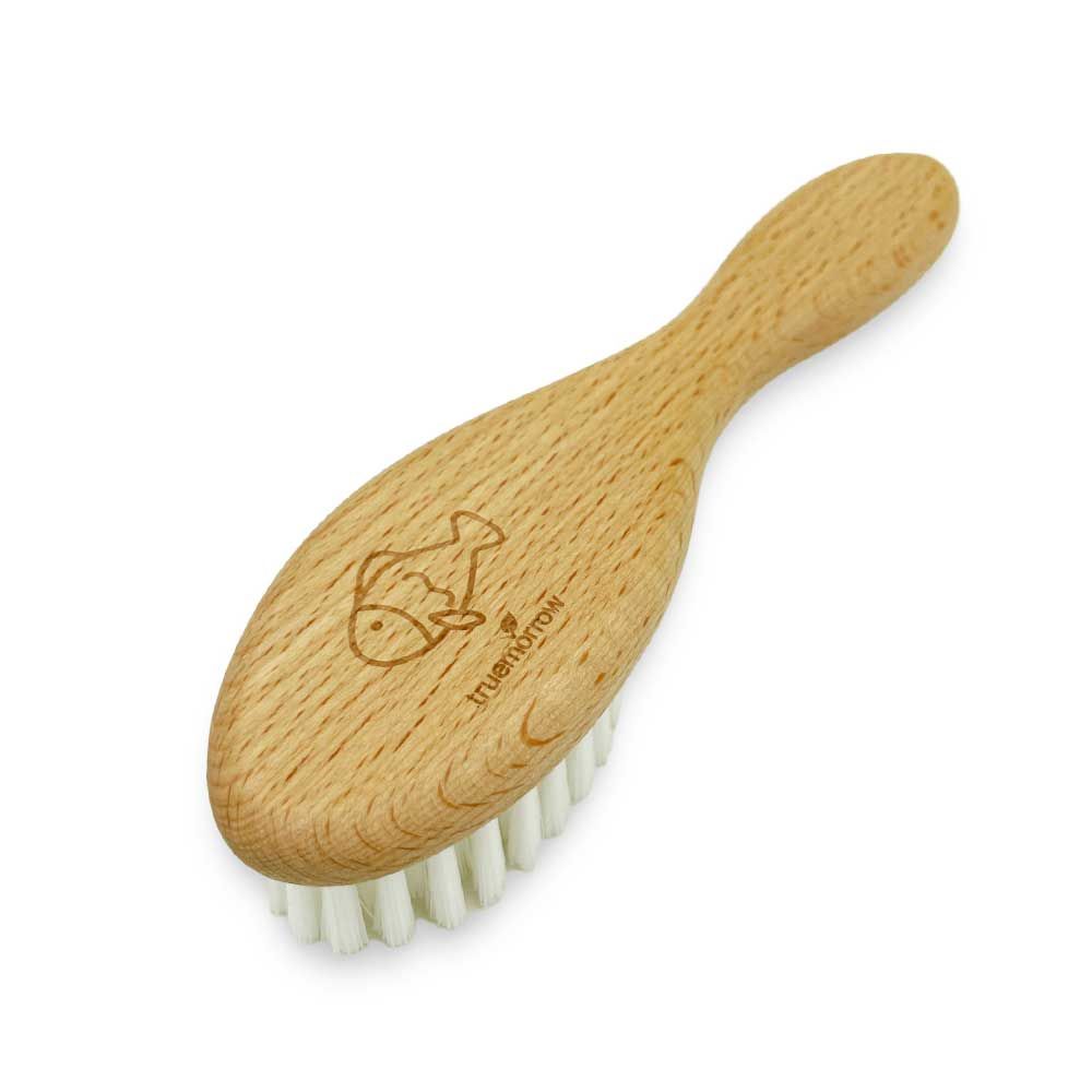Babybürste aus Holz mit Fisch-Logo. Ovaler Bürstenkopf mit weißen Borsten und Holzgriff. Marke: truemorrow.