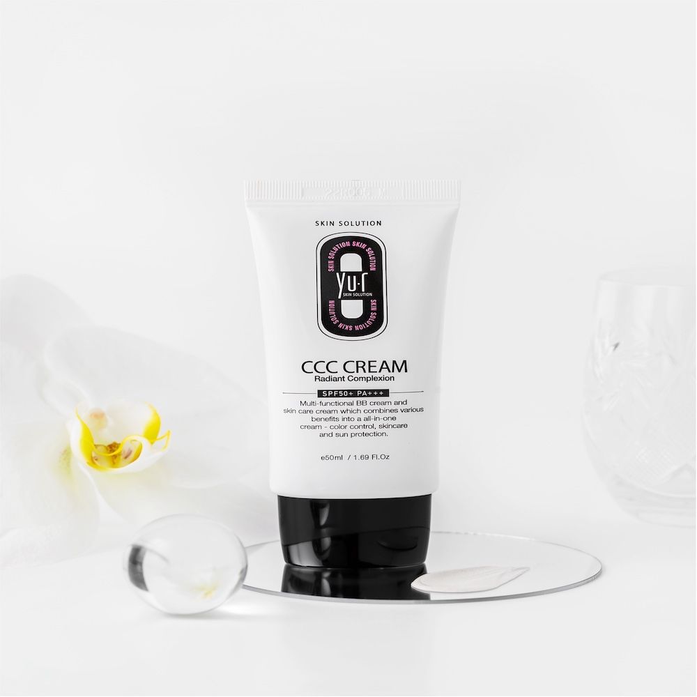 Yu.r CCC Cream Tube auf weißem Hintergrund. Schwarze Schrift. 50ml/1.69 FL.OZ. Mit Orchidee und Spiegel.