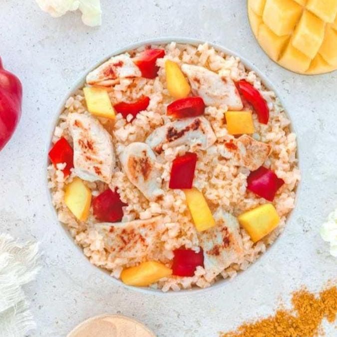 Reisgericht mit Hähnchen, Mango und Paprika. Draufsicht. Mango- und Paprikastücke. Auf hellem Untergrund.