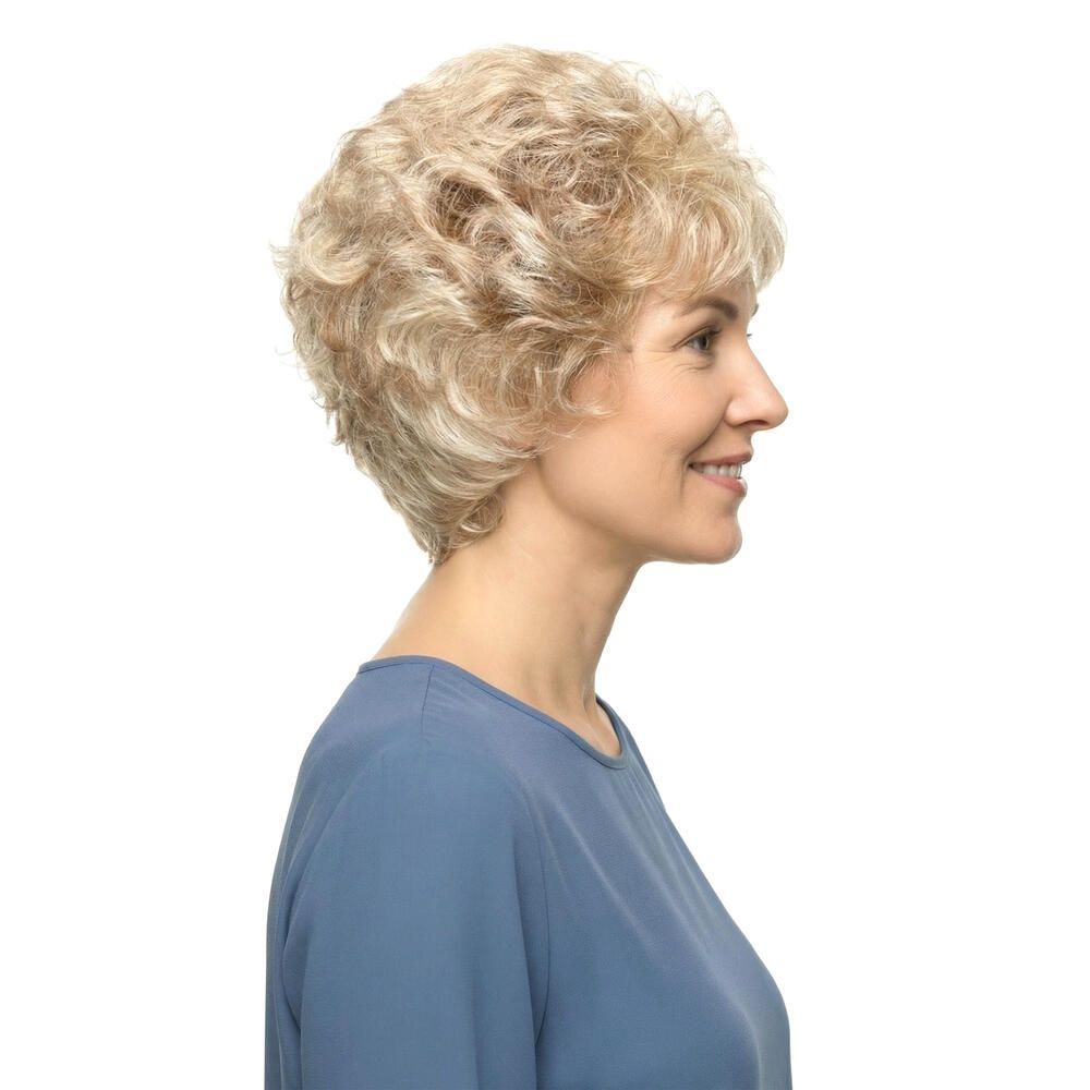 Blond gelockte Perücke. Seitenansicht einer lächelnden Frau mit blauem Oberteil. Kurze, wellige Frisur.