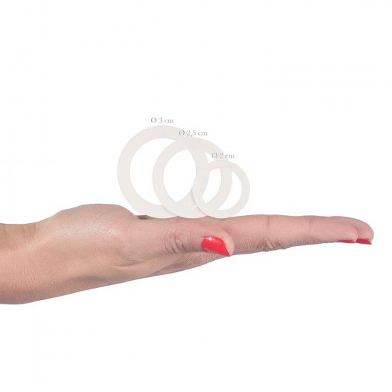 Drei weiße Silikon-Penisringe liegen auf einer Handfläche. Die Ringe haben unterschiedliche Durchmesser.