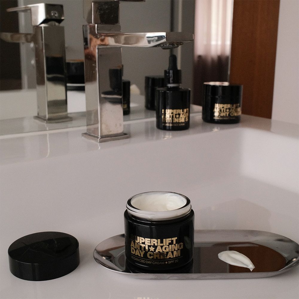 Offener Tiegel mit Creme auf silberner Ablage. Text: Superlift Anti-Aging Day Cream. Weitere Produkte im Hintergrund.