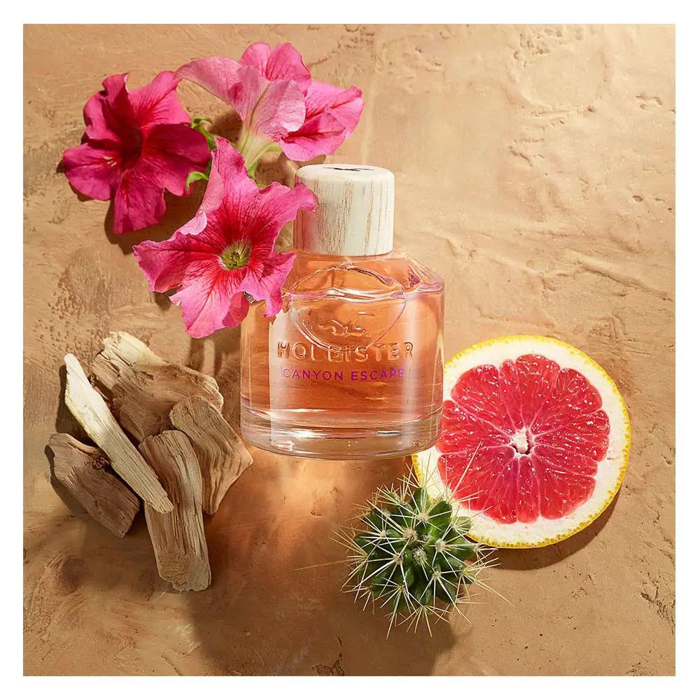 Hollister Canyon Escape Eau de Parfum Spray-Flasche mit Holzverschluss. Umgeben von Blumen, Holzstücken, Grapefruit und Kaktus.